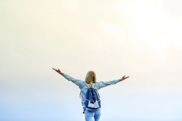 La muchacha feliz con la mochila a la puesta del sol — Foto de Stock