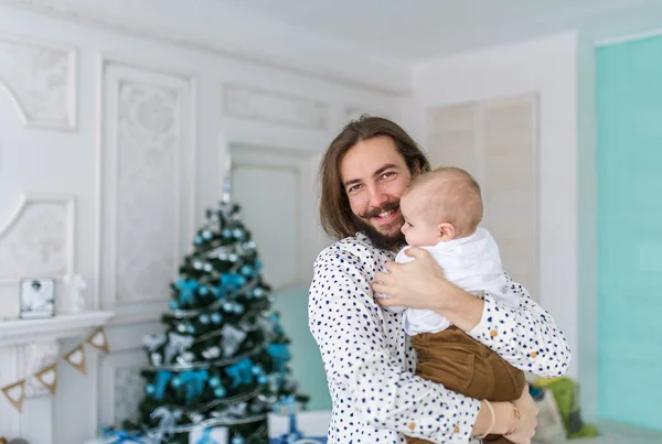Retrato de padre feliz y adorable bebé contra el telón de fondo festivo doméstico con árbol de Navidad — Foto de Stock