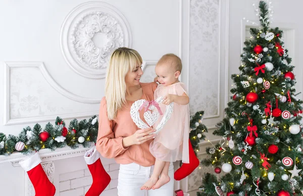 Madre joven con la niña delante del árbol de Navidad — Foto de Stock