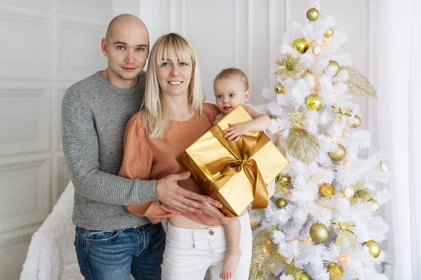 Joven familia feliz mientras se celebra la Navidad en casa . — Foto de Stock