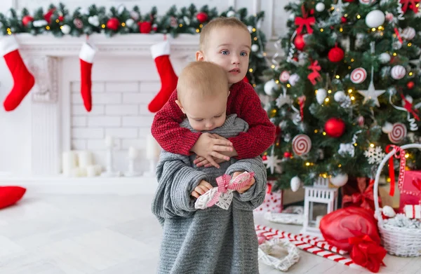 Der Bruder umarmt die kleine Schwester an Weihnachten. — Stockfoto