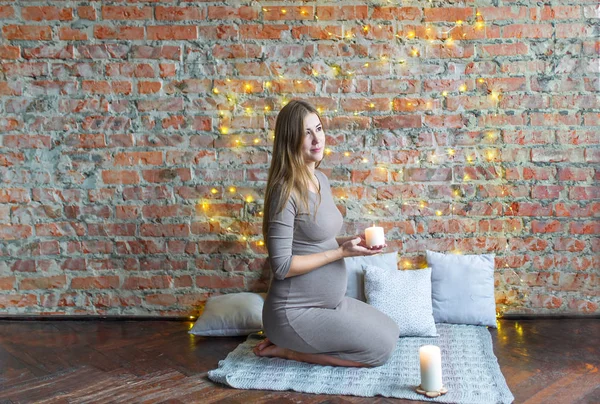 Майбутня мати сидить на підлозі і тримає свічку — стокове фото