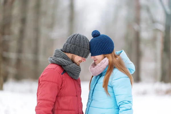 Young couple in the winter wood. Their eyes are hidden under caps. — Stock Photo, Image