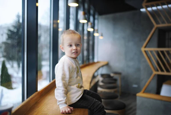 Portrait of little boy sitting on bar counter in cafe. — Stock Photo, Image