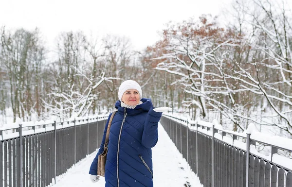 Mujer adorable adulta con abrigo azul con capucha disfrutando paseando en el bosque de invierno al aire libre . — Foto de Stock