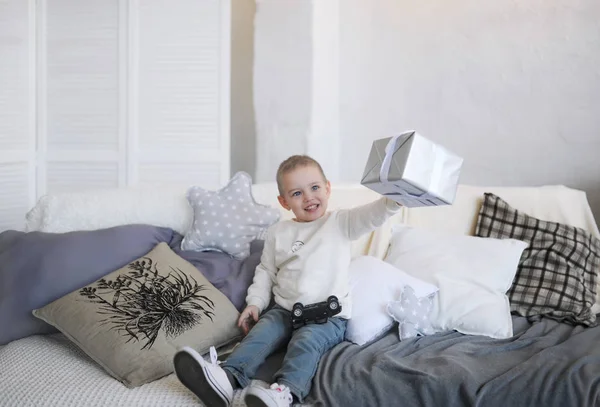 The boy sits on sofa with gifts at the birthday. — Stock Photo, Image