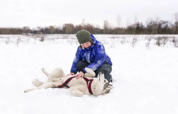 Mujer propietaria con perro husky jugar en la nieve en el día de invierno —  Fotos de Stock