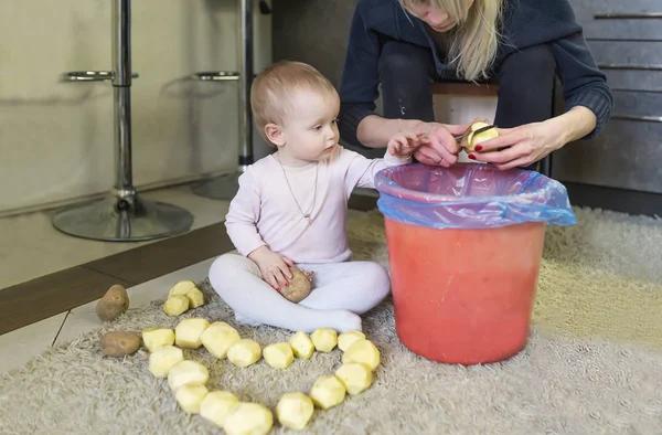 Den lille jenta hjelper moren med å skrelle poteter. Potethjerte – stockfoto