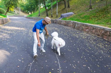 Genç Hintli Park beyaz tüylü bir köpek ile bir dinlenme vardır.