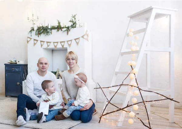 Retrato de familia feliz de cuatro sentados en el suelo en habitación blanca en casa — Foto de Stock