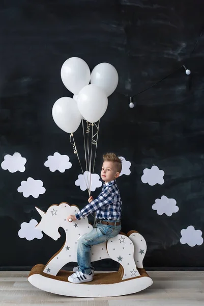 可爱的小宝贝男孩骑传统摇动木马玩具在房间里。用气球男孩. — 图库照片