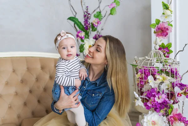 Vista laterale di allegra bella giovane donna che tiene la bambina tra le mani e la guarda con amore — Foto Stock