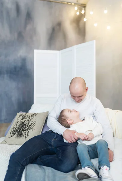 Любящий отец и ее маленький сын сидят дома на диване. Счастливы вместе . — стоковое фото