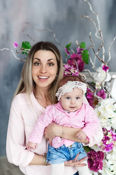 Mutter und Tochter umarmen sich. schöne Frau mit Kind Mädchen. Studioporträt mit Blumen. weibliches Modell. — Stockfoto