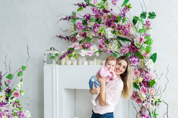 Madre e hija abrazan. Hermosa mujer con niña. Retrato de estudio con flores. Modelo femenino . — Foto de Stock