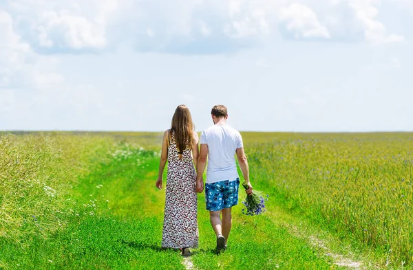 Um casal feliz caminhando juntos em um campo verde — Fotografia de Stock
