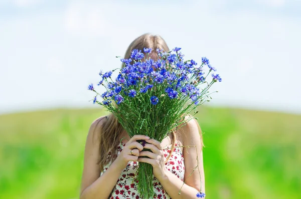 Hermosa joven con un ramo de flores en el prado de verano — Foto de Stock