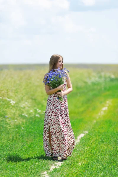 Hermosa joven con un ramo de flores en el prado de verano —  Fotos de Stock