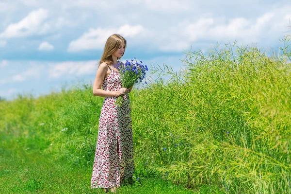 Hermosa joven con un ramo de flores en el prado de verano — Foto de Stock