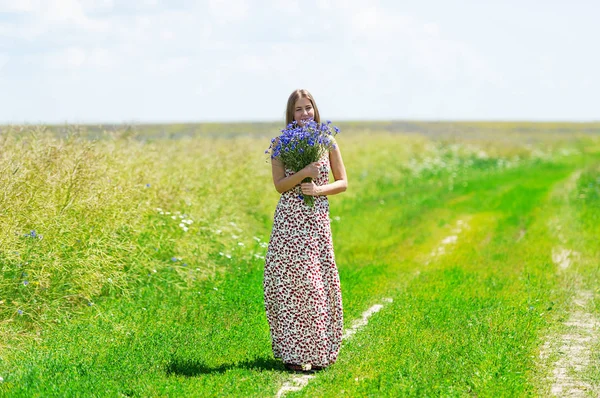 Piękna młoda kobieta z bukietem kwiatów na łące lato — Zdjęcie stockowe