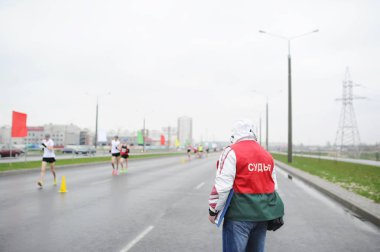 Spor yargıç Maraton Parkuru izliyor. Bir grup insan Gomel sokaklarında, arka