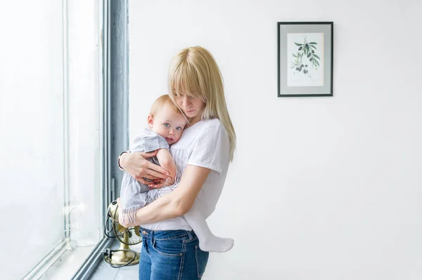 Eine kleine Tochter in der Hand seiner Mutter am Fenster — Stockfoto