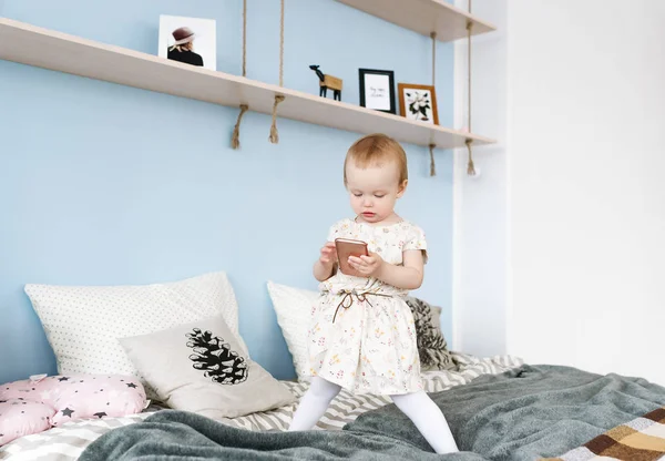 Adorável menina acordou em sua cama, jogando no telefone — Fotografia de Stock