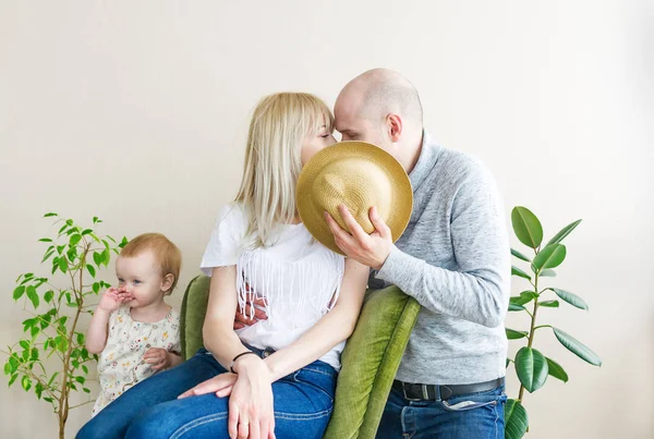 両親にキス、大きな麦わら帽子に隠れている非表示。近くに小さな娘スタンド — ストック写真