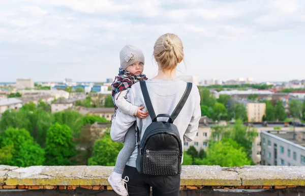 Portrait of young mother and daughter travellers, standing on city roof. Rear view — Stock Photo, Image
