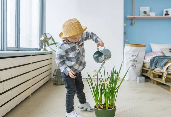 Cute boy in straw hat with a watering can. Watering plant — Stock Photo, Image