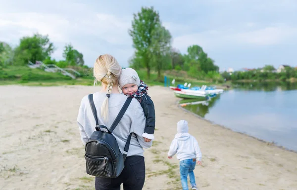 Mor och hennes två barn promenera längs den pittoreska flodstranden — Stockfoto