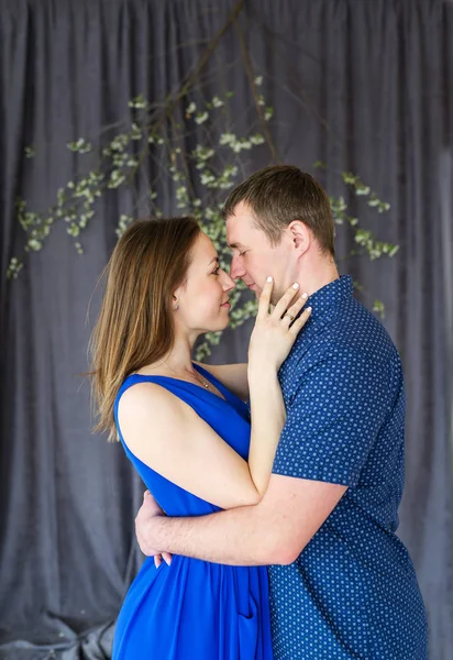Vista lateral de amar jovem casal abraçando contra o pano de fundo de uma cortina — Fotografia de Stock