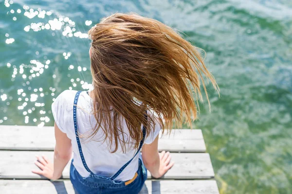 Junges schönes Mädchen sitzt auf Steg Fluss im Hintergrund — Stockfoto