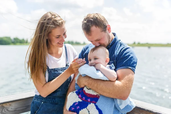 Mãe e pai com o bebê filho de pé no cais junto ao rio — Fotografia de Stock