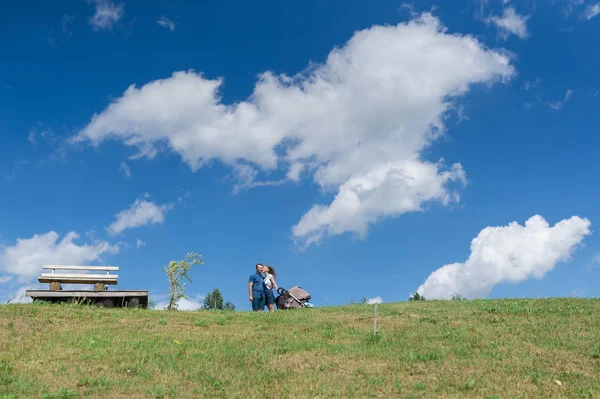 Lycklig familj med bebis på fältet. Grönt fält under blå himmel. Sommarlandskap — Stockfoto