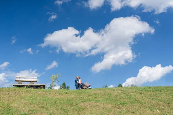 Lycklig familj med bebis på fältet. Grönt fält under blå himmel. — Stockfoto