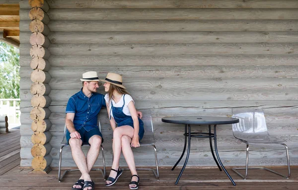Молодая пара в шляпах на фоне стены деревянного дома — стоковое фото
