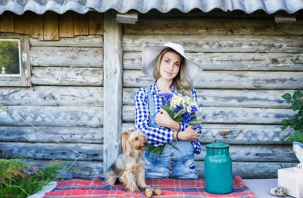 Mujer joven en un sombrero de paja de verano y su pequeño perro rural fondo —  Fotos de Stock