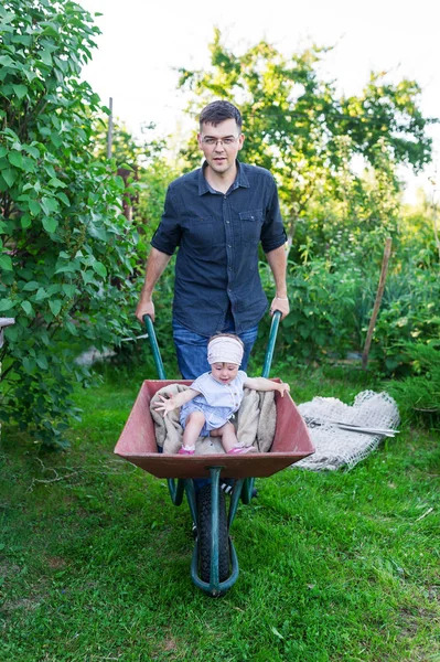 Vader spelen met baby dochter met trolley in dorp — Stockfoto
