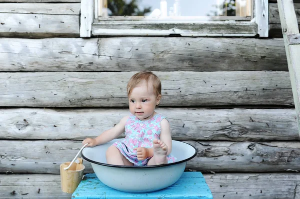 Bir duvar ahşap evin arka planı yikarken kapta küçük güzel bebek kız