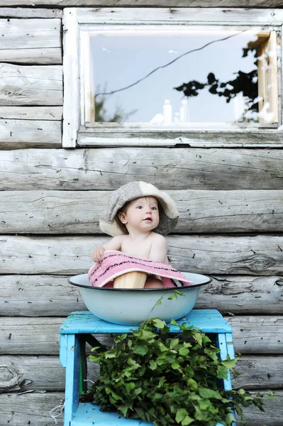 Bir duvar ahşap evin arka planı yikarken kapta küçük güzel bebek kız