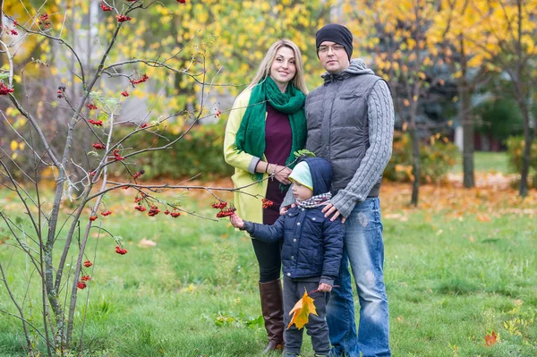 Familia feliz de tres de pie juntos en el jardín en otoño — Foto de Stock