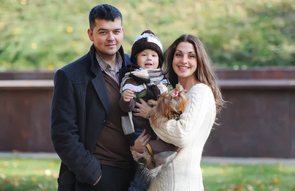 Família feliz de três de pé juntos no parque no outono — Fotografia de Stock