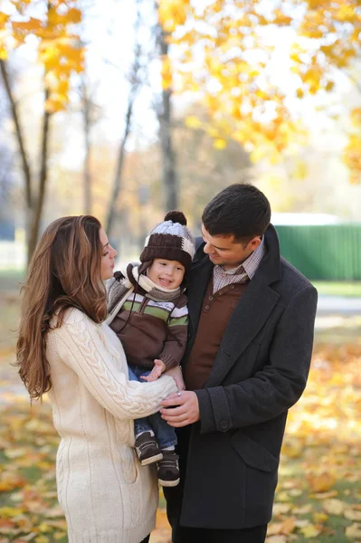 Familia feliz de tres de pie juntos en el parque en otoño — Foto de Stock