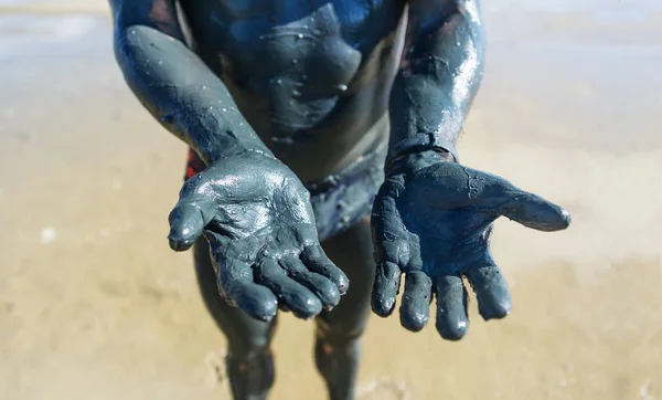 As mãos do homem manchadas com lama negra de cura . — Fotografia de Stock