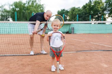 Kel baba ve tenis kortunda küçük kız portresi.