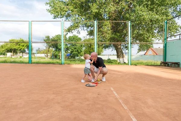 Батько цілує доньку на тенісному корті. Ніжні почуття батька і дочки . — стокове фото