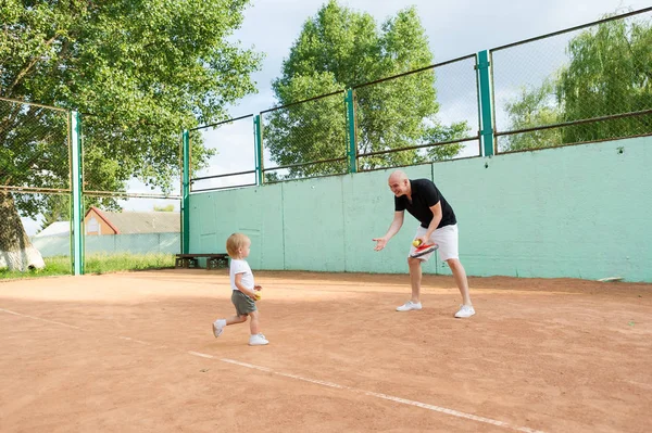 Веселий батько і маленька дочка грають на тенісному корті — стокове фото