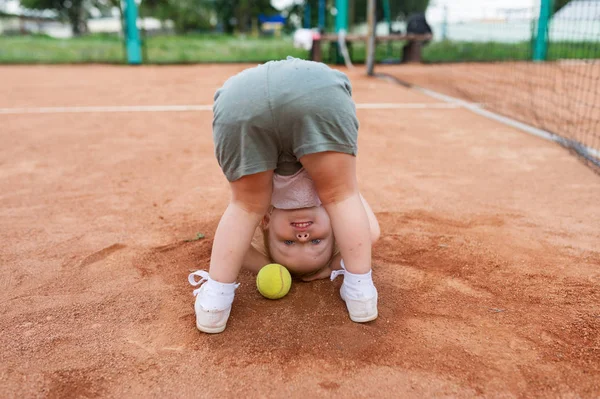 Rückansicht eines lustigen kleinen Mädchens mit Tennisball auf dem Tennisplatz. — Stockfoto