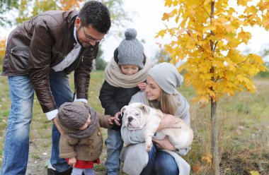 Anne, baba, çocuklar ve bulldog açık havada iki köpek yavrusu. Sonbahar açık havada.